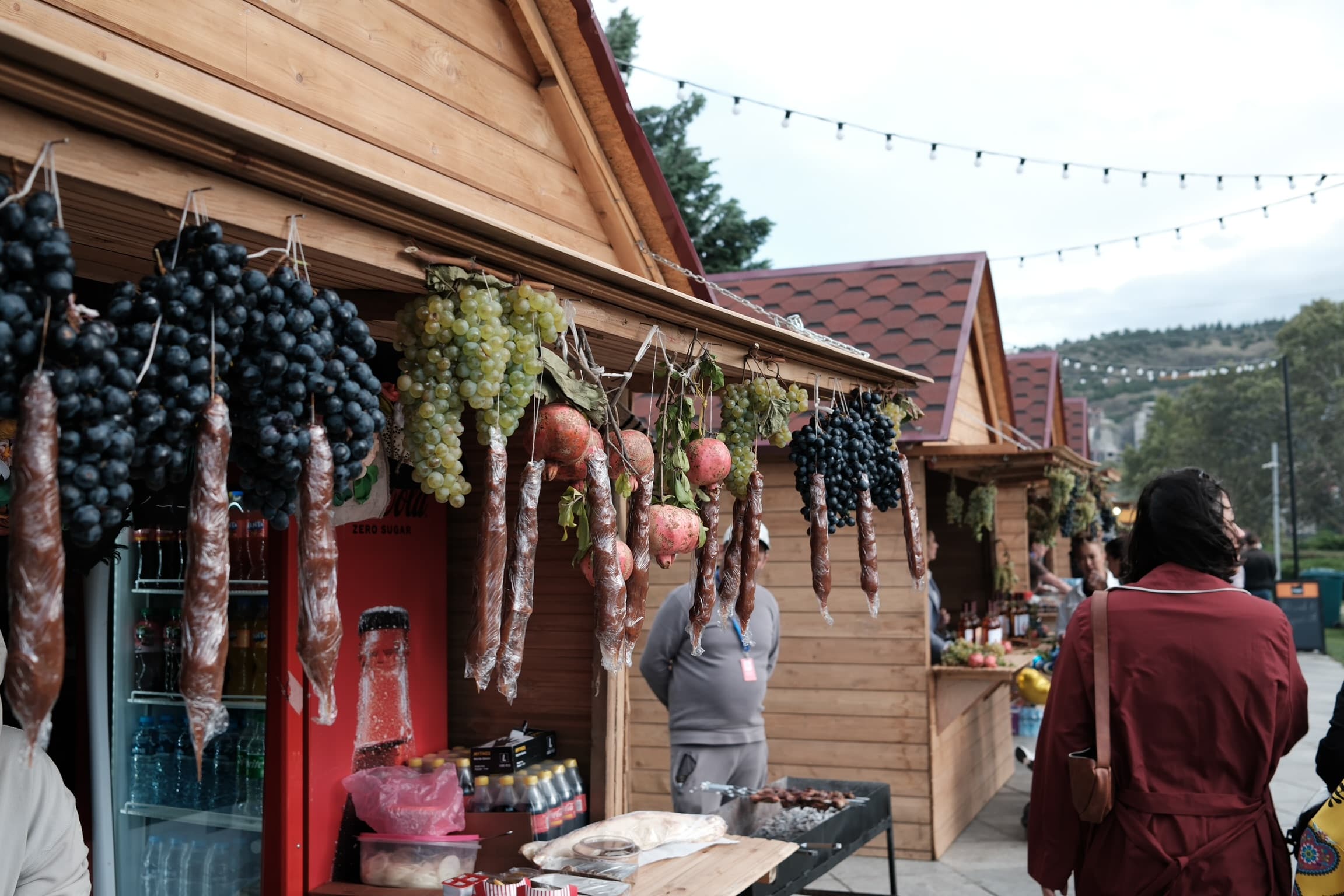 Georgian market - grapes, pomegranates, and churchkhela hanging at a Rtveli festival stall